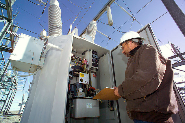 Field engineer inspecting an open electrical substation cabinet at a critical-infrastructure site.